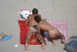 Some middle-aged couples sunbathing on nudist beach.
